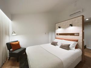 a bedroom with a large white bed and a chair at Alto do Ferrum - Boutique Villa in Covilhã