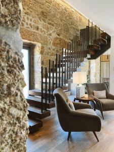 a living room with two chairs and a staircase at Alto do Ferrum - Boutique Villa in Covilhã