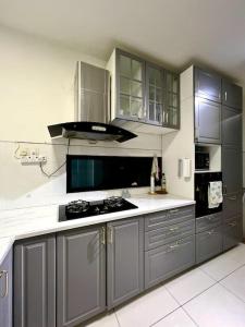 a kitchen with gray cabinets and a stove top oven at Lapan Ompek Homestay 3 Bedrooms in Nilai