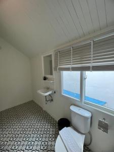 a bathroom with a toilet and a sink and a window at RoomQuest Rim Praya Dinsor Road in Bangkok