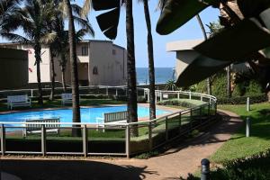 een zwembad met twee banken en de oceaan bij Surfside Ballito - Family Only in Ballito