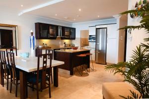 een keuken met een tafel, stoelen en een koelkast bij Surfside Ballito - Family Only in Ballito