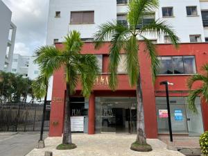 a red building with palm trees in front of it at Hermoso Apartamento con Piscina 1 Habitacion PR32 in Montería