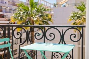 Hotel La Villa Nice Promenade في نيس: طاولة زرقاء على شرفة مع أشجار النخيل