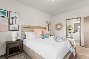 - une chambre dotée d'un grand lit avec des draps blancs et des oreillers roses dans l'établissement Brand New 2 Bed 2 Bath Near Perry District and DT, à Spokane