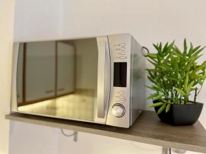 a microwave sitting on a shelf with a potted plant at Studio le pied de Bœuf in Wissembourg