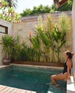 a woman sitting on the edge of a swimming pool at Ke Rensia Private Pool Villas Gili Air in Gili Islands