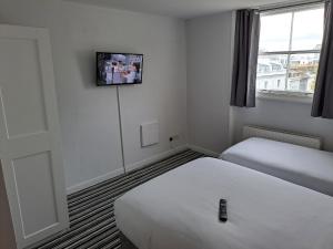 a hotel room with two beds and a tv on the wall at Palace Court Hotel in London