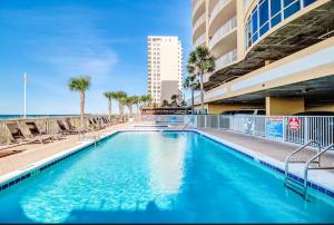 - une piscine avec des chaises et l'océan en arrière-plan dans l'établissement Ocean Villa 1206, à Panama City Beach