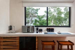 a kitchen with a counter with a microwave and a window at Aalada Playa del Carmen in Playa del Carmen