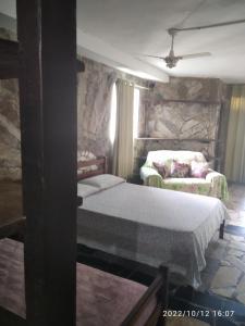 1 dormitorio con 2 camas y pared de piedra en Kit net Carlotta Apartmentos, en Salvador