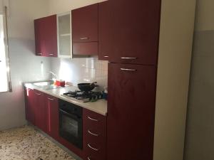 a kitchen with red cabinets and a stove top oven at Appartamento relax a Catanzaro Lido in Catanzaro