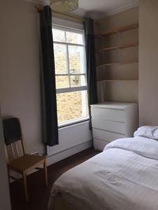 a bedroom with a bed and a window and a chair at Elegant 3bed Crouchend in style with roof terrace in London