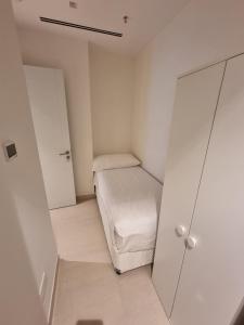 Shaqa at Address Beach Residence - Fuj في الفجيرة: غرفة بيضاء صغيرة بها سرير وخزانة
