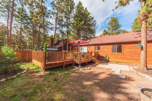 ein Blockhaus mit einer Terrasse und einem Sonnenschirm in der Unterkunft Blissful Mountain Escape in Woodland Park