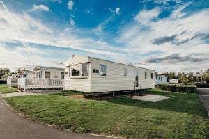 a white mobile home in a yard with a driveway at Waterside, Thorpe Park Cleethorpes Static Caravan in Cleethorpes