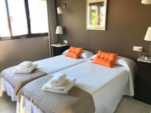 2 camas en una habitación con almohadas y toallas de color naranja en Apartamentos El Hospital de Villahormes, en Villahormes