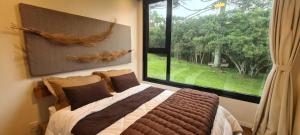 a bedroom with a bed and a large window at Brumas Casa de Campo - Cambará do Sul in Cambara do Sul