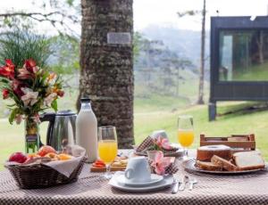 uma mesa com comida para o pequeno-almoço e sumo de laranja e sumo de laranja em Brumas Casa de Campo - Cambará do Sul em Cambará