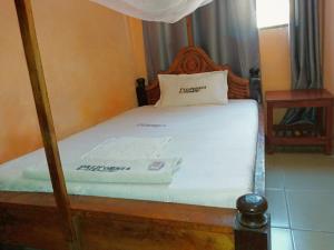 a bedroom with a bed with a wooden bed frame at California Lodge in Bagamoyo