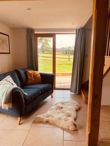 2 Beds & living in our idyllic country Cottage في بيدفورد: غرفة معيشة مع أريكة وسجادة على الأرض