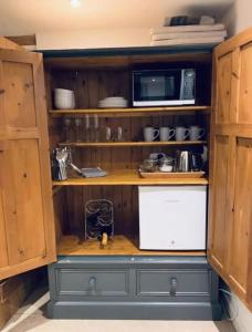 a kitchen with wooden cabinets and a microwave at 2 Beds & living in our idyllic country Cottage in Bedford