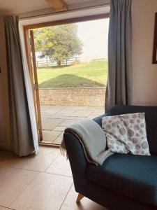 a living room with a blue couch and a sliding glass door at 2 Beds & living in our idyllic country Cottage in Bedford