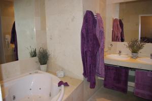 y baño con bañera, 2 lavabos y toallas púrpuras. en Château de Pommeuse, en Pommeuse