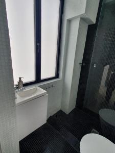 un bagno con un water, un lavandino e una finestra di Casa do Dário a 50 metros da praia de Sesimbra a Sesimbra