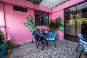 a woman sitting at a table in front of a pink wall at Taybo Beach By St Hoteles in Santa Marta