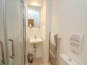 a white bathroom with a sink and a shower at The Mew in Dartmouth