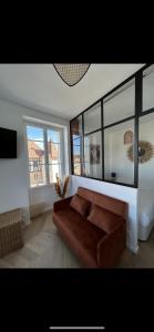 salon z brązową kanapą i 2 oknami w obiekcie La marine w mieście Deauville