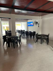 Casa Hotel Estelar في فيلافيجا: غرفة طعام بها طاولات وكراسي وتلفزيون بشاشة مسطحة