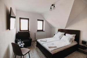 um pequeno quarto com uma cama e uma cadeira em BORSIKA PENSIUNE & SPA em Căpîlniţa