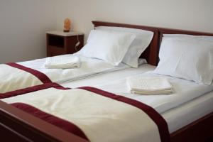 two beds with white sheets and white pillows at Átalvetős Agropanzió in Morăreni