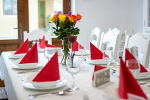 a table with red paper napkins and a vase with flowers at Átalvetős Agropanzió in Morăreni