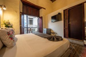 Schlafzimmer mit einem Bett mit einem Fenster und einem TV in der Unterkunft Casa BuGo in Cartagena de Indias