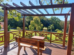 a wooden bench on a deck with a pergola at Pousada Villa Romantica in Nova Petrópolis