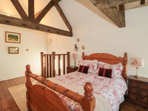 a bedroom with a wooden bed with pillows on it at Pike Cottage in Acton Turville