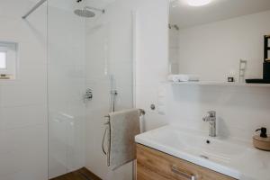 a white bathroom with a sink and a shower at Wein Cottage Kellerstöckl in Eisenberg an der Pinka