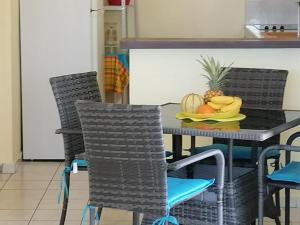 una mesa de comedor con sillas y un plato de fruta. en Villa Rose & F, en Sainte-Anne