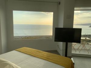 - une chambre avec une grande fenêtre, un lit et une télévision dans l'établissement Los Balcones, à Salobreña