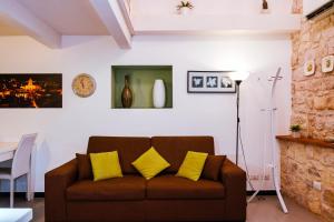 sala de estar con sofá marrón con almohadas amarillas en Casa Basile, en Módica
