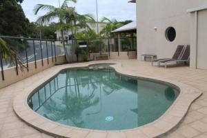 a swimming pool on a patio with a building at Oceanview4 in Nambucca Heads