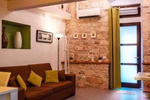 ein Wohnzimmer mit einem braunen Sofa und einer Steinmauer in der Unterkunft Casa Basile in Modica
