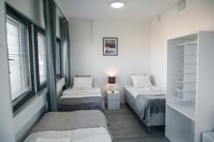 two beds in a room with white walls and windows at Inn Tourist Hostel in Helsinki