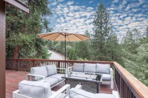 a deck with a table and chairs and an umbrella at Hillside Hideaway - game rm - master spa - Luxury in Lake Arrowhead