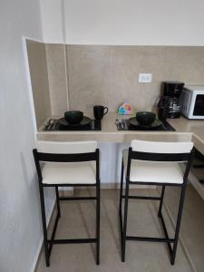 una cocina con 2 sillas y una barra con 2 tazones en Casa en Mahahual cerca de la playa D4 en Mahahual