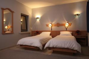 a bedroom with two beds and a mirror and lights at Hotel Sieweburen in Luxembourg