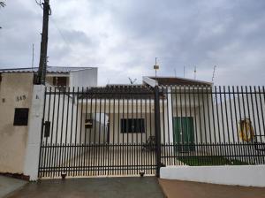 a fence with a white building with a green door at Residencia Cidade Verde 14 in Maringá